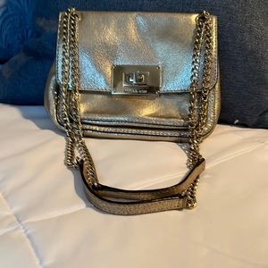 Michael Kors gold nurse with gold chain and leather strap.